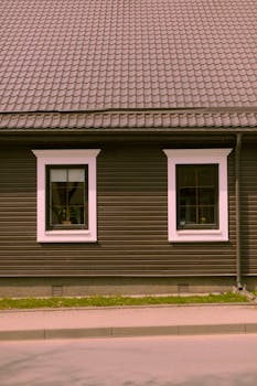A cozy wooden house facade showcasing two windows and a tiled roof, ideal for architectural themes.