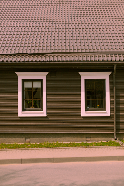 A cozy wooden house facade showcasing two windows and a tiled roof, ideal for architectural themes.