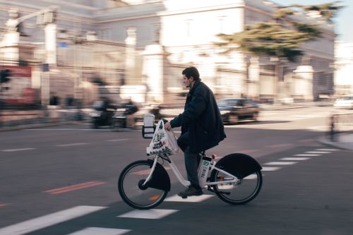 Free A man rides an electric bike through the urban streets of Madrid, Spain. Stock Photo