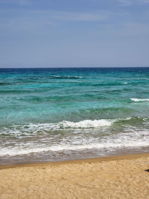 Free Peaceful beach scene with turquoise waves and golden sand in Gazimağusa. Stock Photo