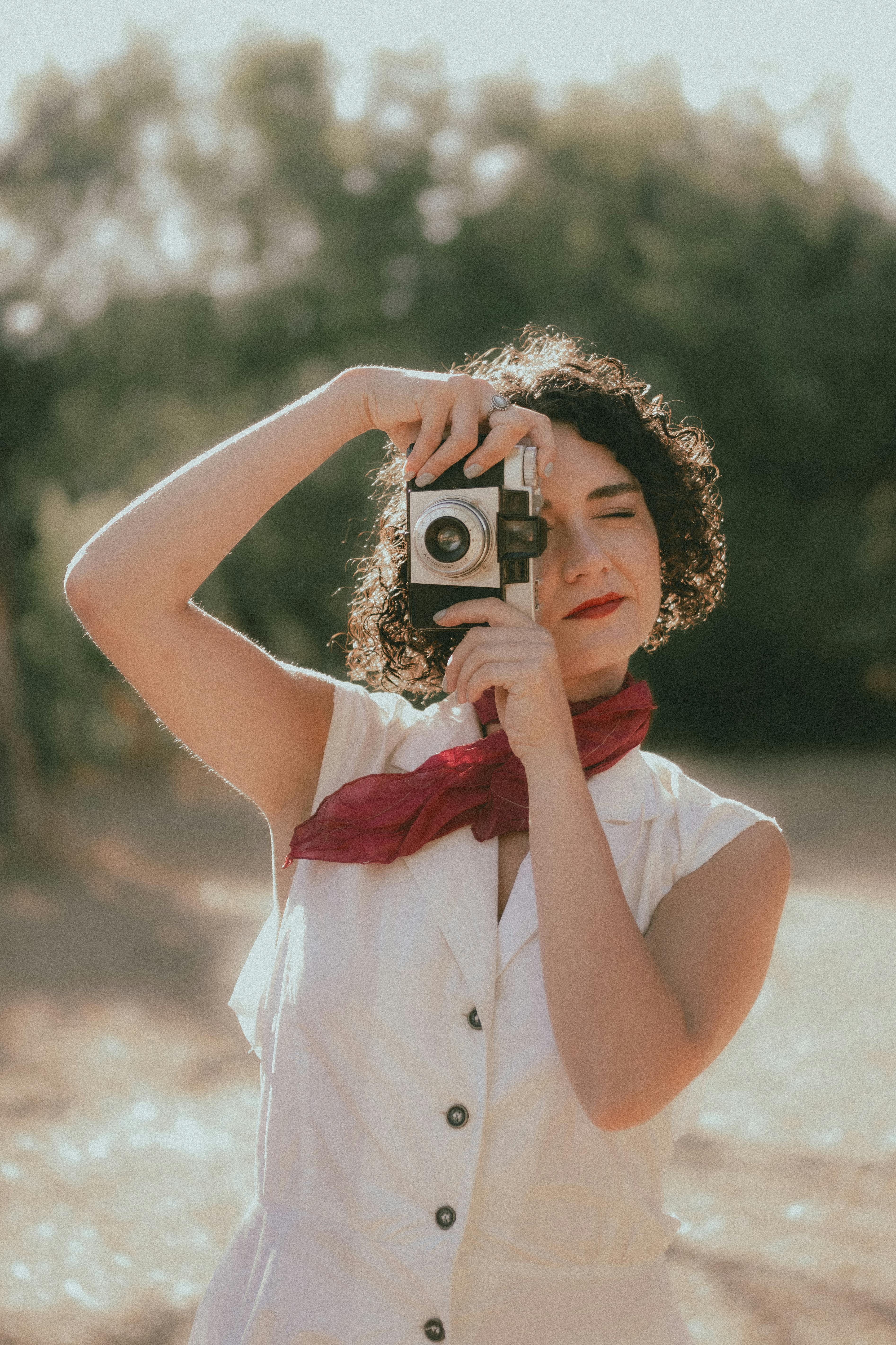 在户外，一位身着复古服饰的女性正在使用经典相机捕捉永恒的瞬间
