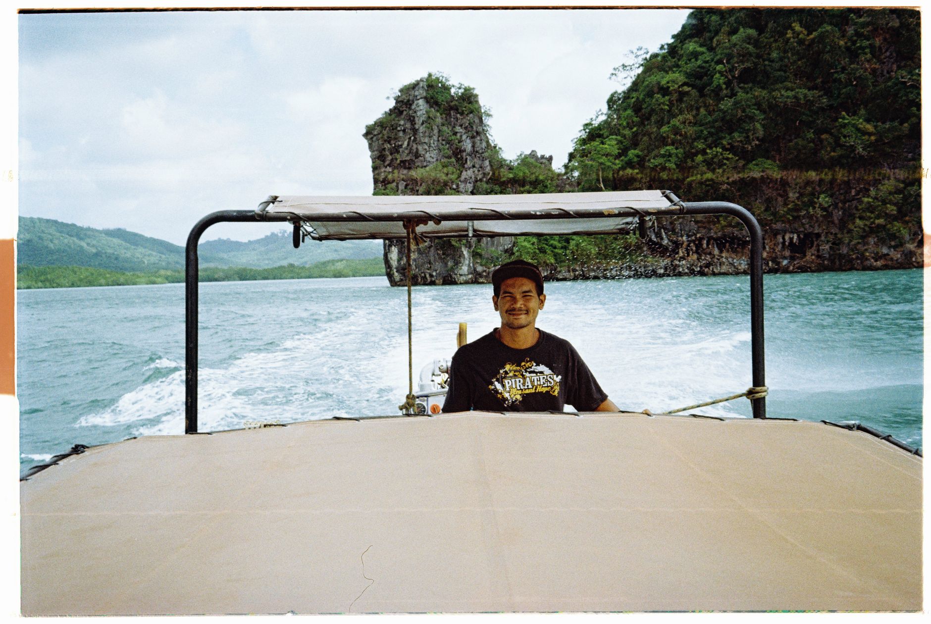 A man navigating a motorboat through clear waters in scenic Phuket, Thailand.