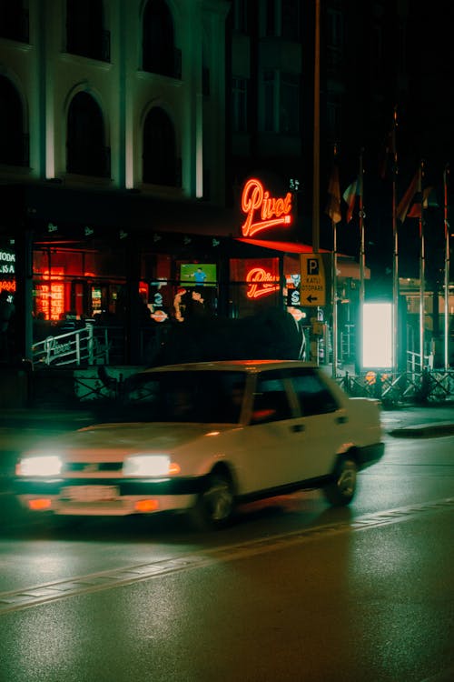 Car Driving Past Hotel with Glowing Neon Sign