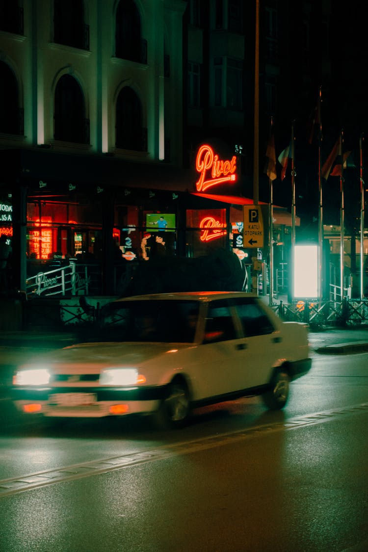 Car Driving Past Hotel With Glowing Neon Sign