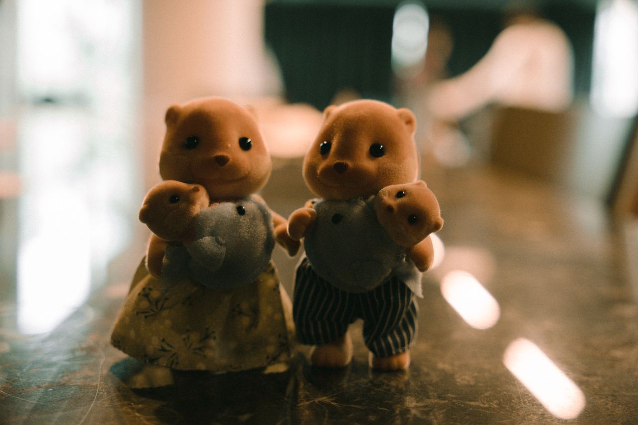fuzzy toy animals with baby figures standing indoors with soft lightin