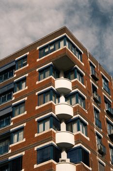 Sunlit corner view of an urban apartment building with balconies and windows.