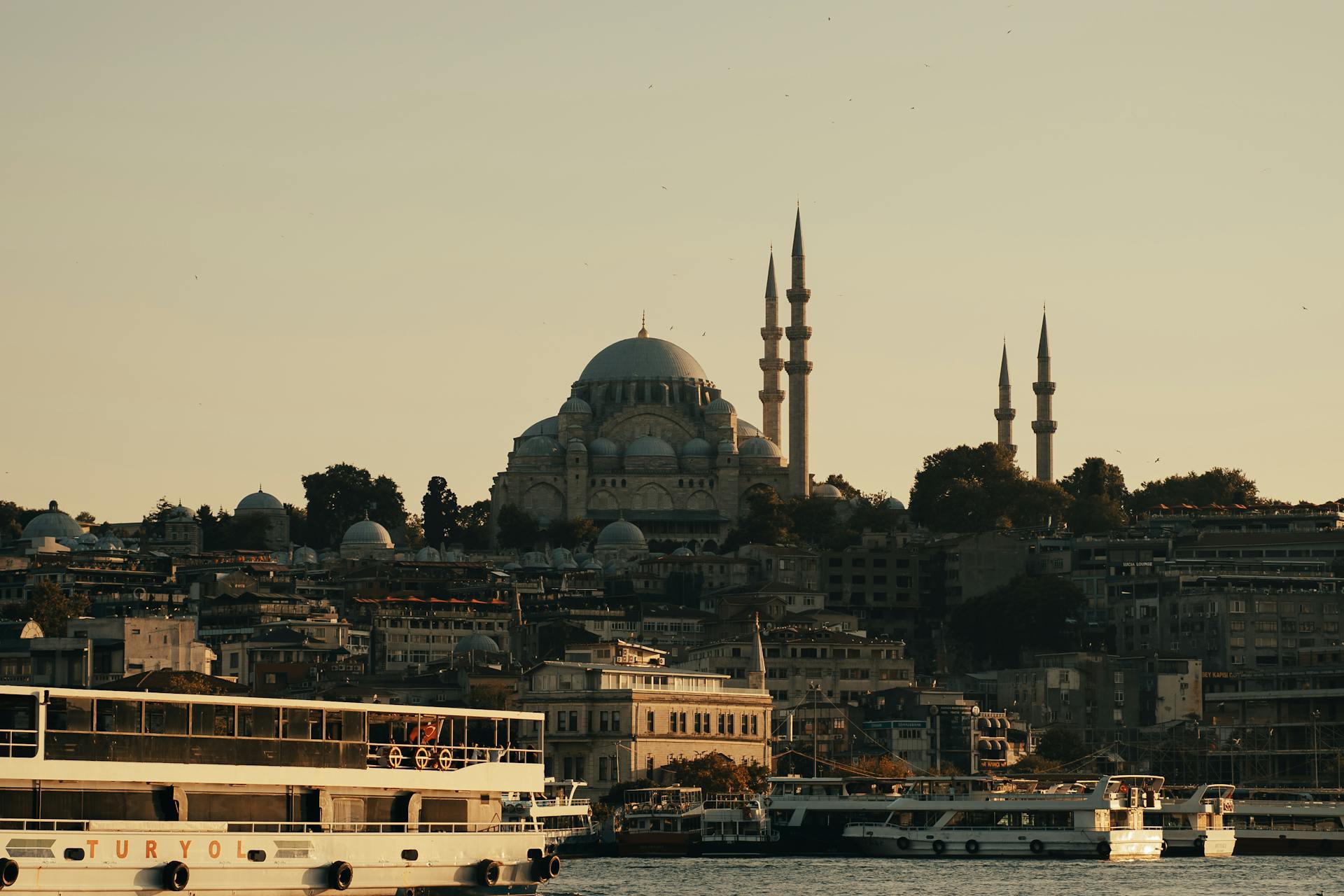 Istanbul skyline at sunset with Suleymaniye Mosque and ferries on the Bosphorus.