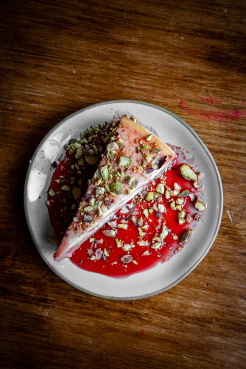 Free Close-up of a pistachio cake slice with fruit sauce on a white plate. Stock Photo