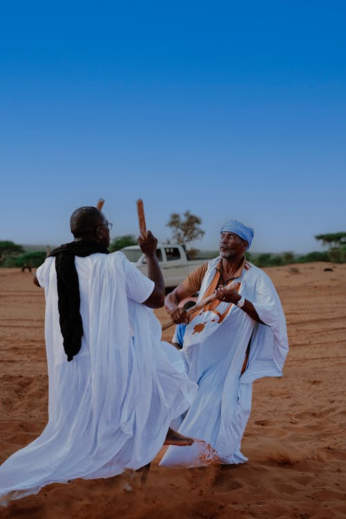 Men in White Gowns on Sand