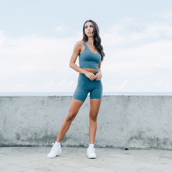 Runner in a plain teal two-piece kit on a sea wall — bamboo ave. on Pexels