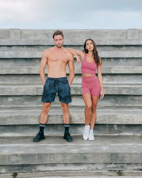 Muscular couple in athletic wear posing on outdoor concrete steps in an urban setting, Austin, TX.