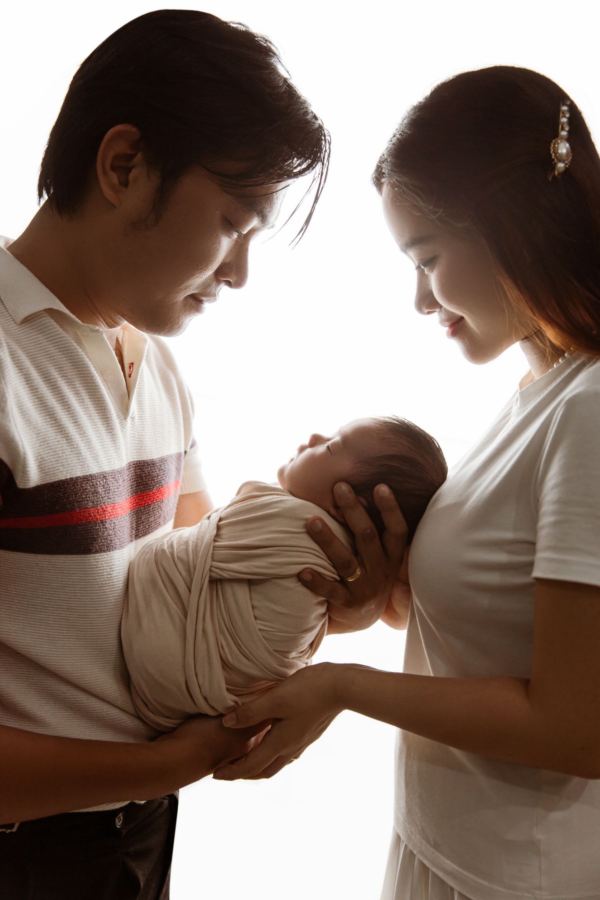 Parents gently holding their newborn baby together