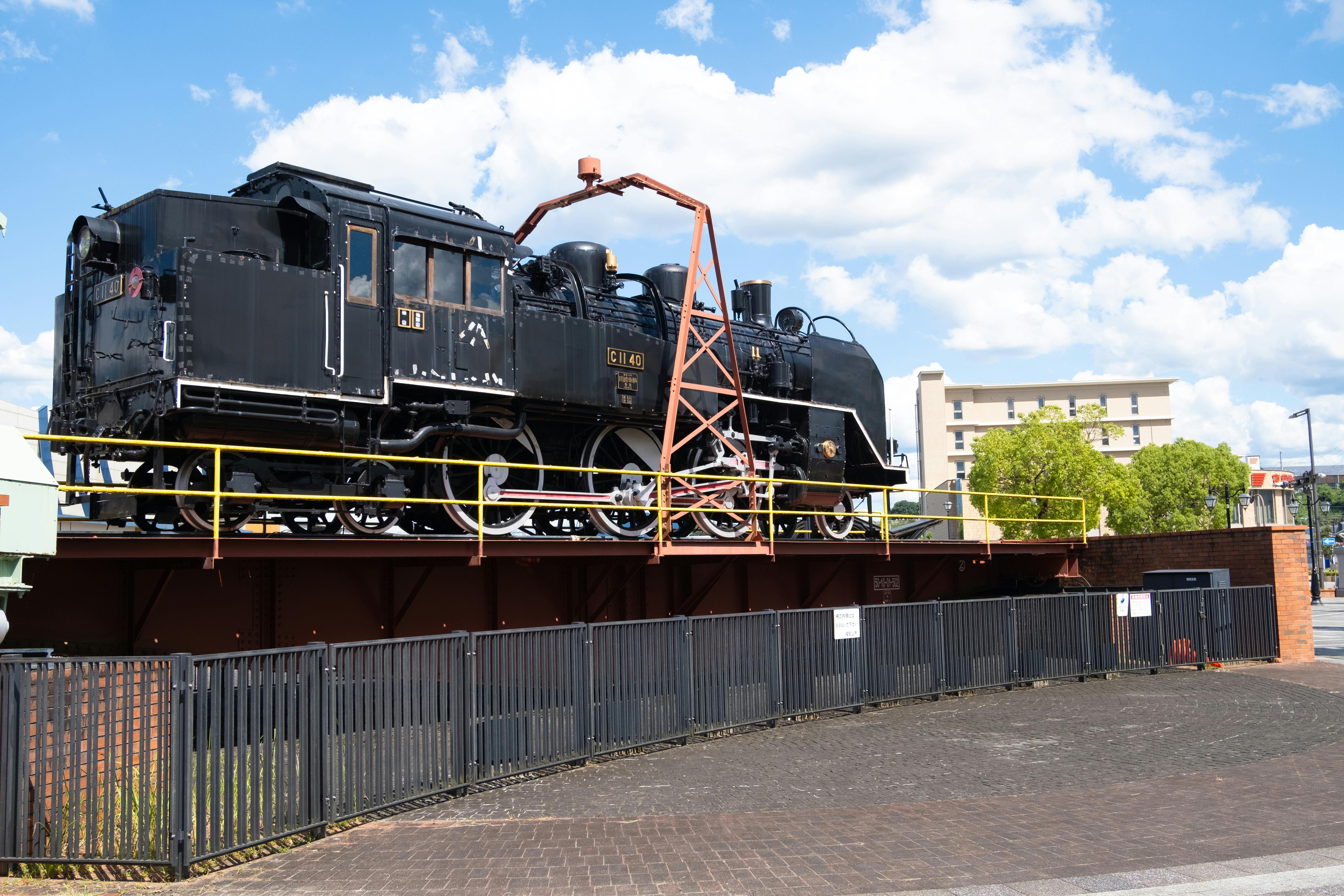 Vintage steam train on display in Kyoto, Japan, showcasing industrial heritage in an urban setting.