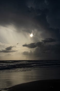 Moody ocean scene with storm clouds and dark horizon over the beach.