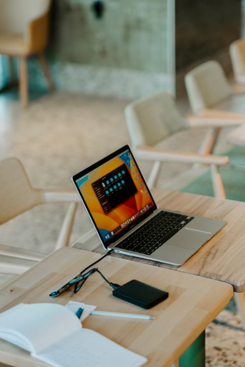 Free A sleek laptop with accessories on a wooden table in a stylish office setting. Stock Photo