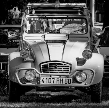 Black and white image of a vintage Citroen 2CV parked at an outdoor motor show.