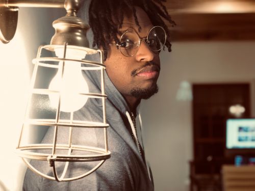 Free Portrait of man in hoodie with eyeglasses near vintage lamp indoors. Stock Photo