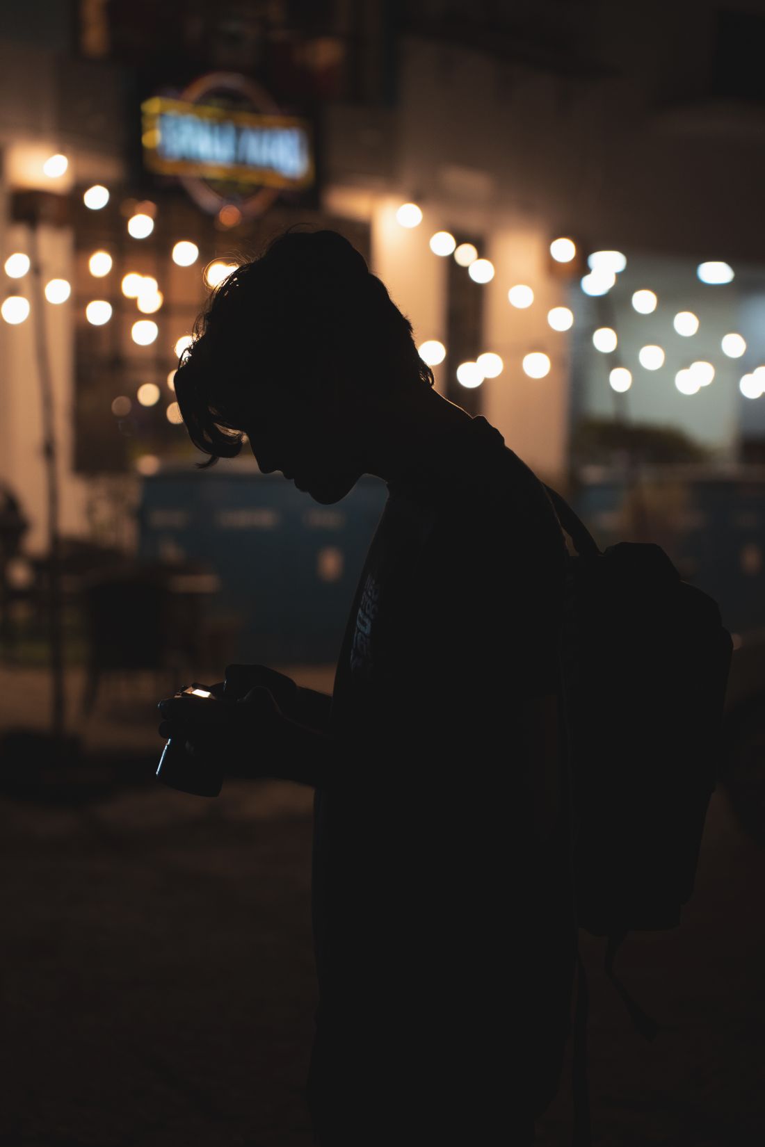 A photographer silhouetted against the lights of a city at night