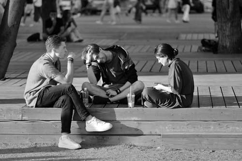 Black and White Photo of Young People Sitting on a Bench