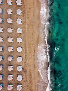 Captivating aerial view of Naxos beach with aligned umbrellas and turquoise waves.
