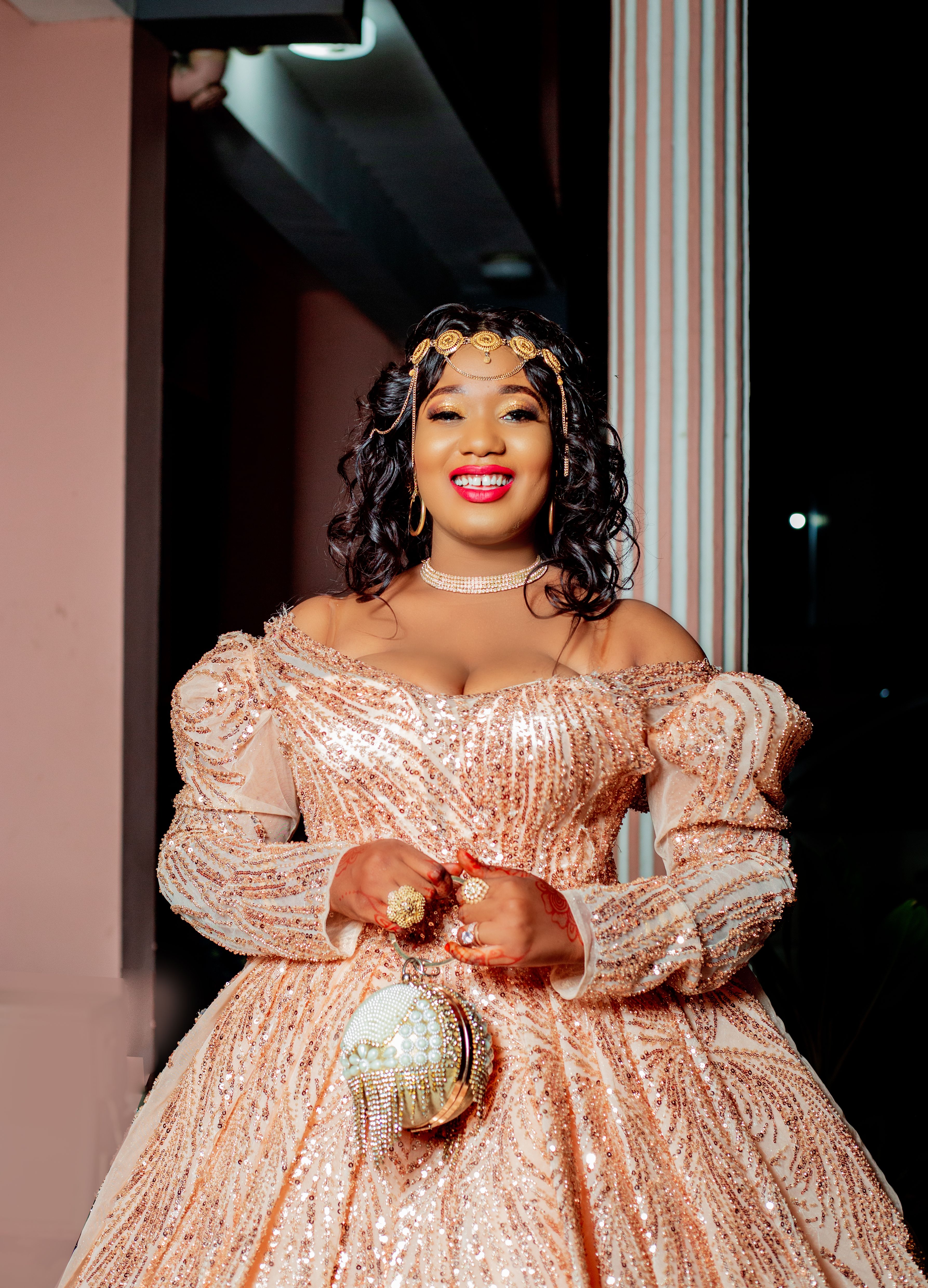A woman in a glamorous sequined gown smiling confidently indoors at night.