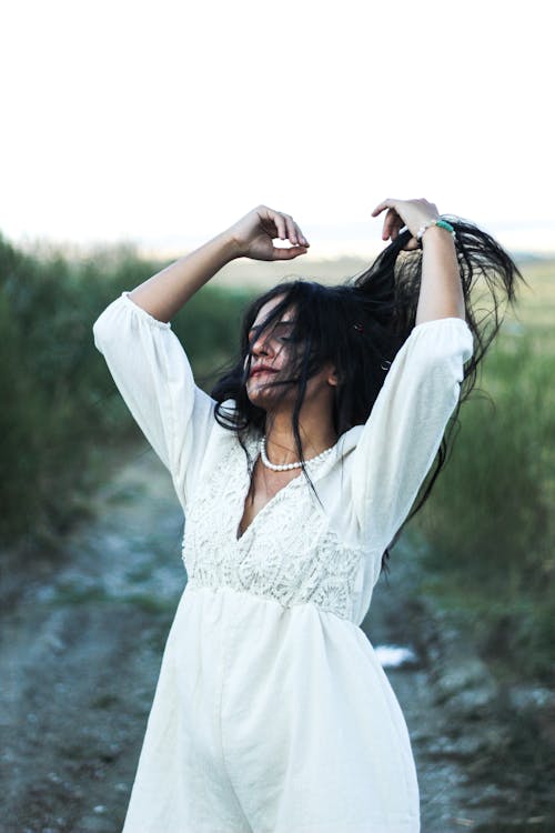 Woman in White Dress Standing on Dirt Road