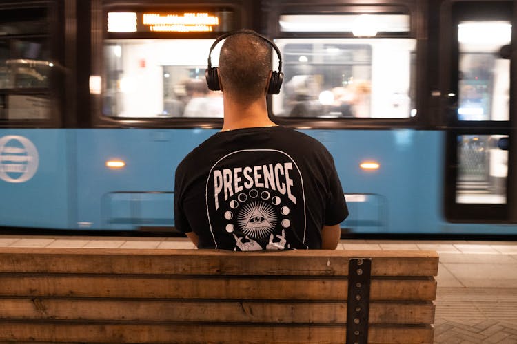 Man In Headphones Sitting On Urban Bench