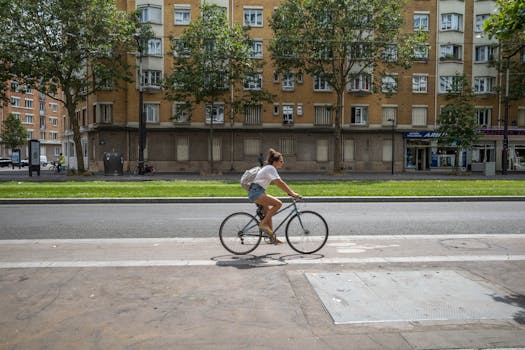 Woman cycling on an urban street bike lane beside a row of buildings.