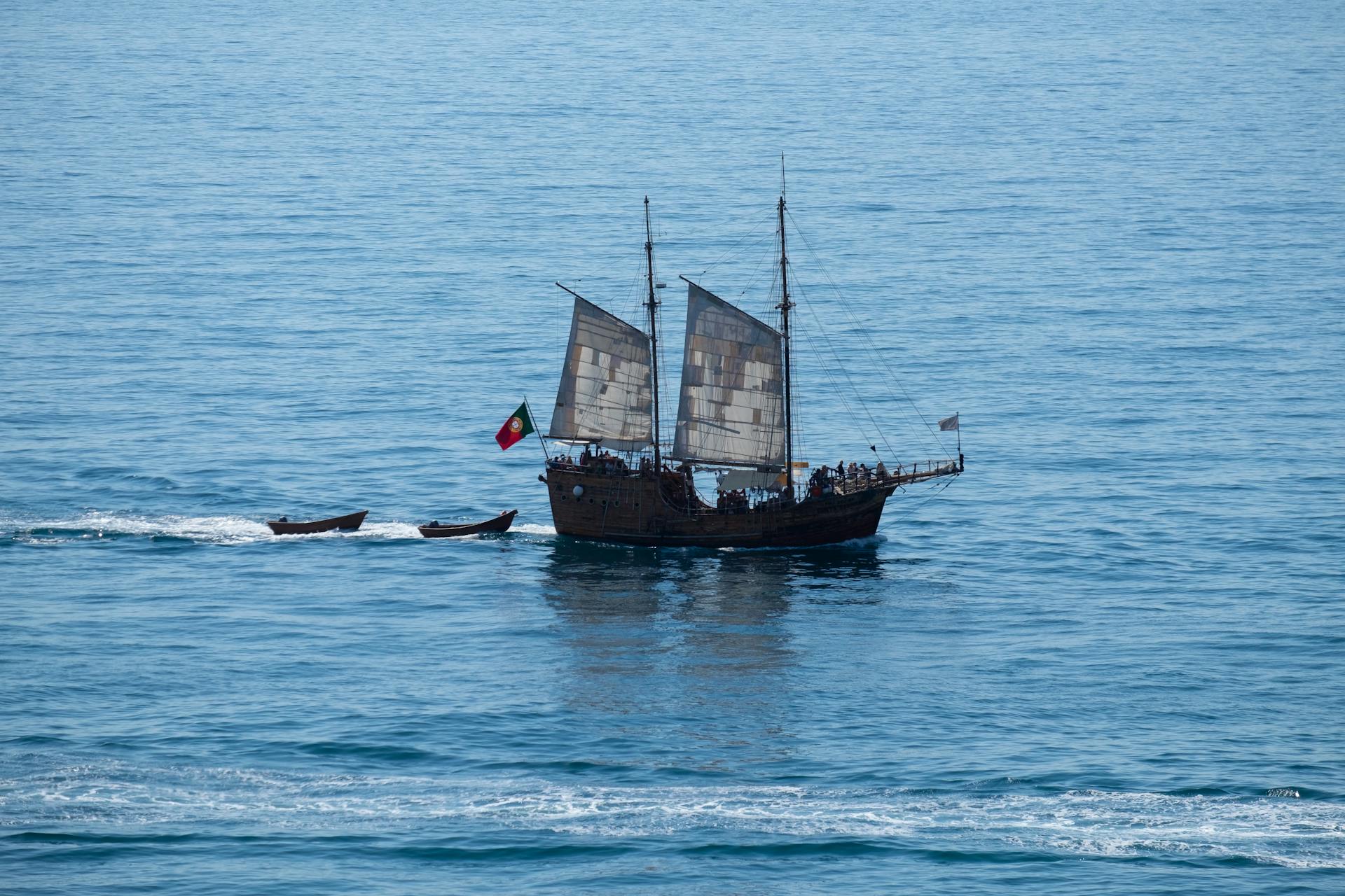 A vintage sailing ship with Portuguese flag cruising the vast ocean waters.