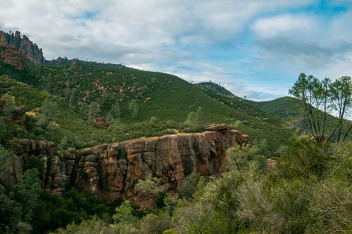 Free Beautiful view of lush green hills and rocky cliffs under a cloudy sky, capturing natural serenity. Stock Photo