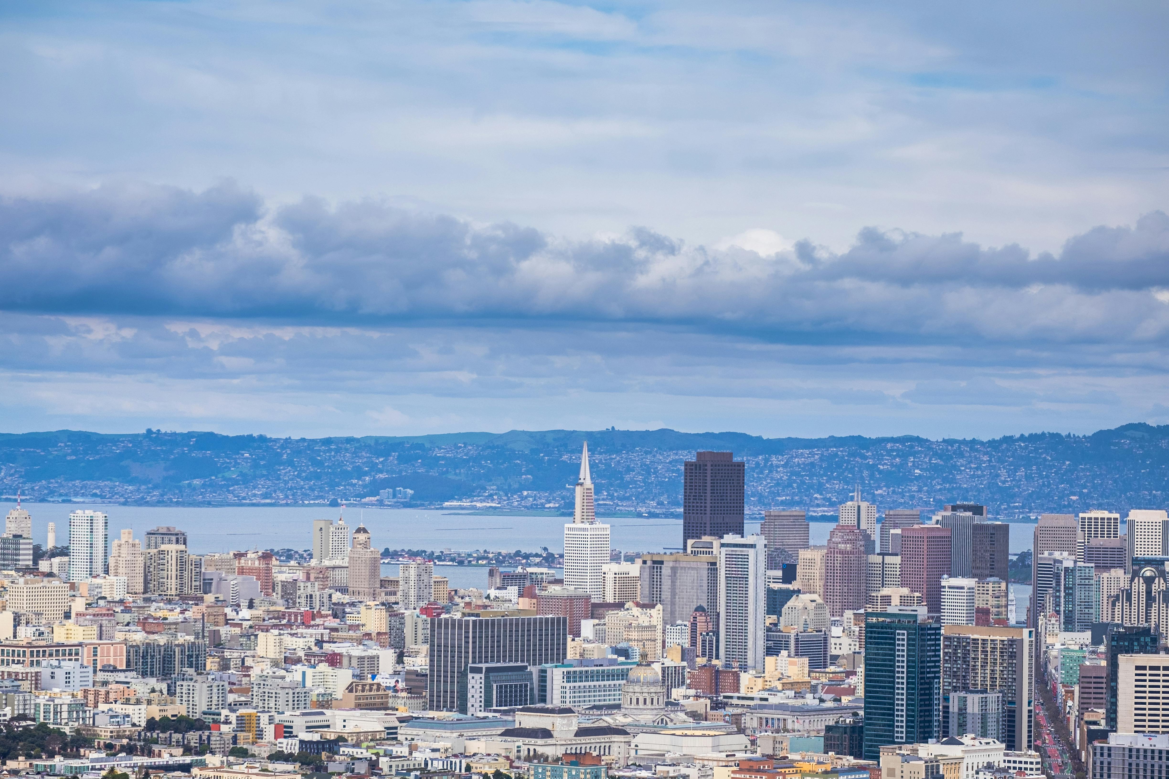 Stunning aerial view of San Francisco skyline with Bay Area in the background under cloudy skies.