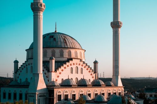 Free A stunning exterior view of a mosque featuring Ottoman architecture with prominent minarets and dome at sunset. Stock Photo