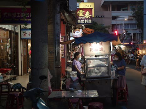 Bustling night street market scene with food stands and people in an urban setting.