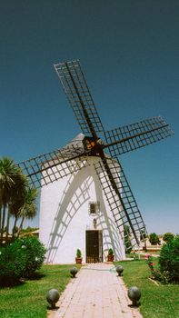 Iconic windmill in La Mancha, Spain, under a clear blue sky on a sunny summer day.