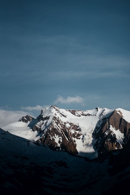 Free A breathtaking view of a snow-covered mountain peak with a clear blue sky backdrop. Stock Photo