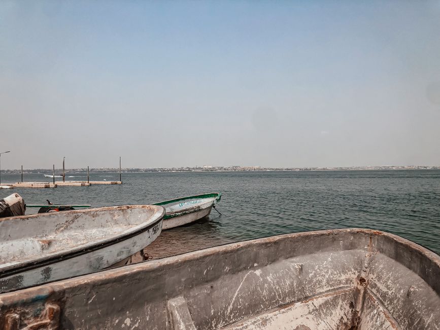 Rustic boats moored by the coast in Belas, Angola with a hazy horizon.