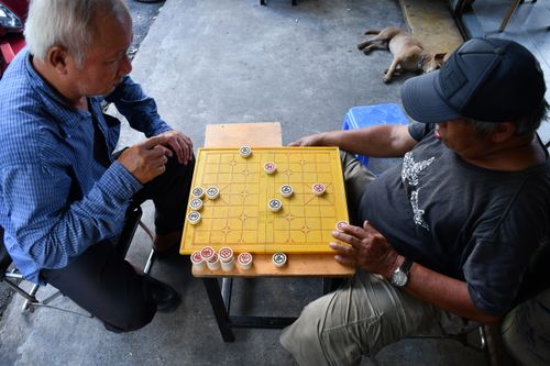 Free Senior men playing a traditional board game outdoors in Ho Chi Minh City, Vietnam. Stock Photo