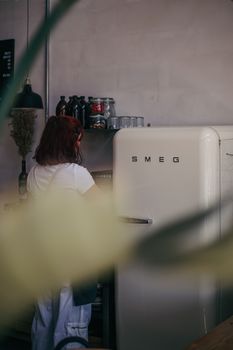 Woman standing near a retro Smeg fridge in a cozy, stylish kitchen.