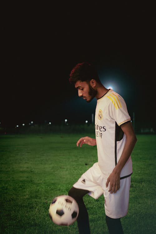 A boy playing football in a field on night time