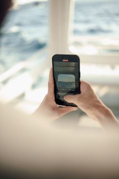 Hands holding a phone above open water — photo by Tahir Osman on Pexels