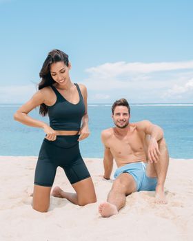 A fashionable couple smiling and enjoying a sunny day on the beach.