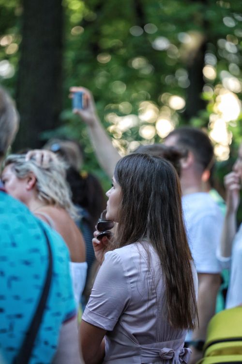 Free People gathered outdoors, enjoying a summer event with greenery around. Stock Photo