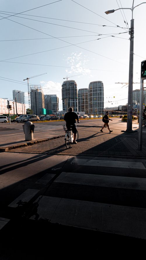 Free Urban scene with modern architecture, pedestrians, and a cyclist at a city intersection during the day. Stock Photo
