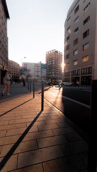 City street view capturing sunset reflections on buildings, highlighting urban life.