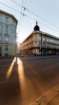 Sunlight casts long shadows on a quiet city street lined with historic buildings.