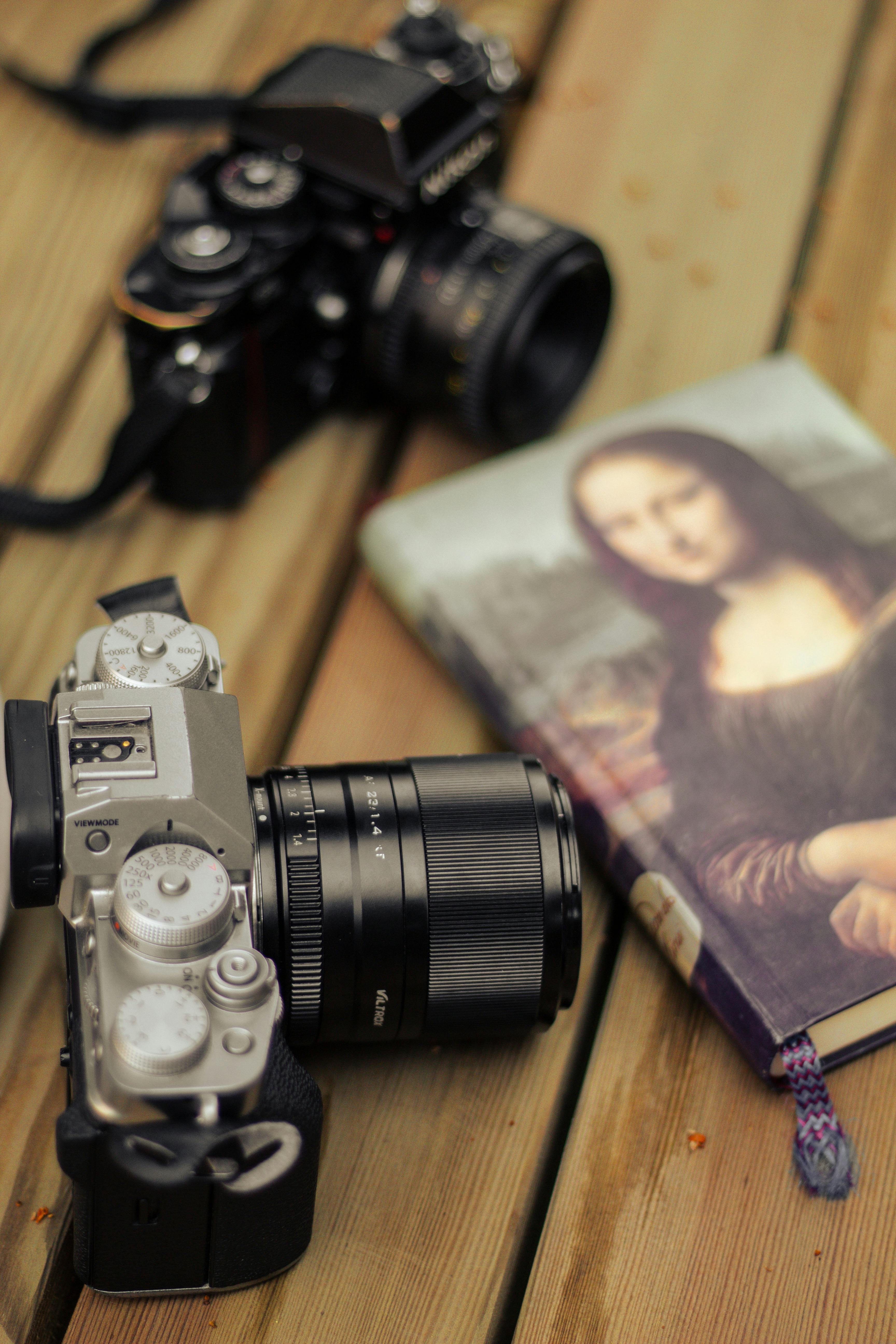 Close-up of vintage cameras and a book with Mona Lisa on a wooden table.