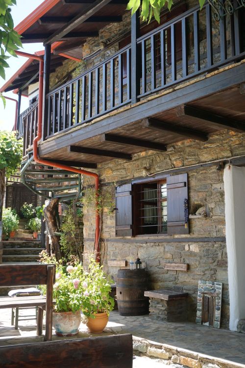Free Rustic stone house with wooden balconies and lush plants in Ano Skotina, Greece. Stock Photo