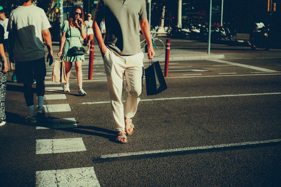 Pedestrians moving through hard afternoon light on a city street, the setting that turns an easy sandal into a real wearability test.