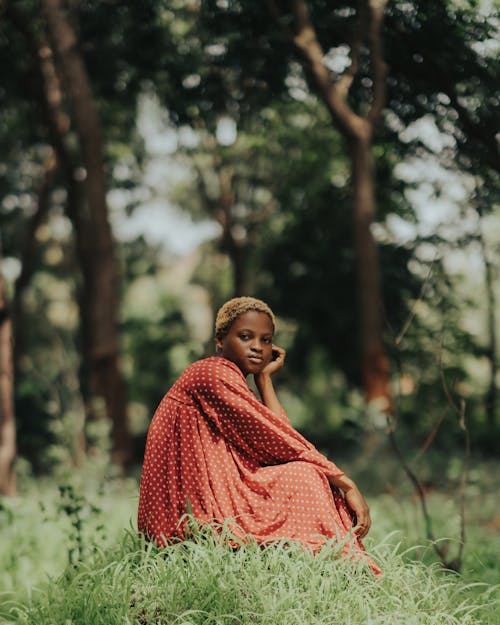 Woman in Red Dress Sitting among Trees