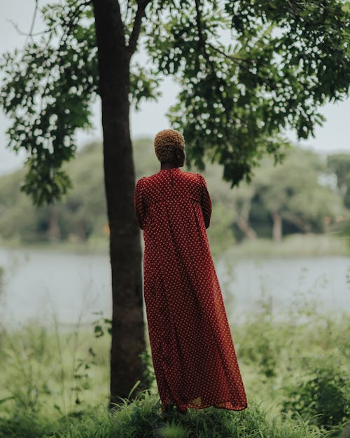 Woman in Long Spotted Dress Standing on Meadow